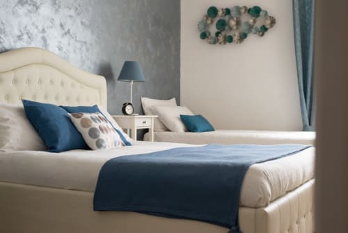 Elegant bedroom at UrbanFlat Roma with cream upholstered bed, blue accents, and modern furnishings in contemporary apartment.