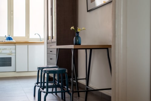 Modern UrbanFlat Roma apartment kitchen with dining table, bar stools, and city view in contemporary style