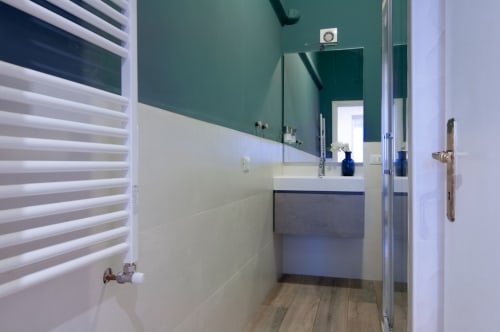 Modern bathroom in UrbanFlat Roma with teal and white design, vanity sink, and walk-in shower