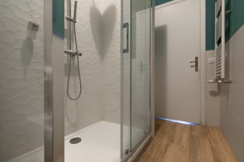 Modern bathroom with walk-in shower, white tile walls, and wooden flooring at UrbanFlat Roma apartment