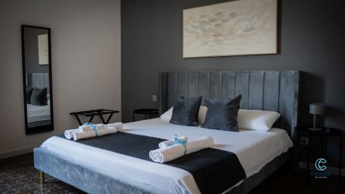 Camera moderna di Moon Rooms By Celeste a Catania con letto imbottito grigio, biancheria bianca e asciugamani arrotolati