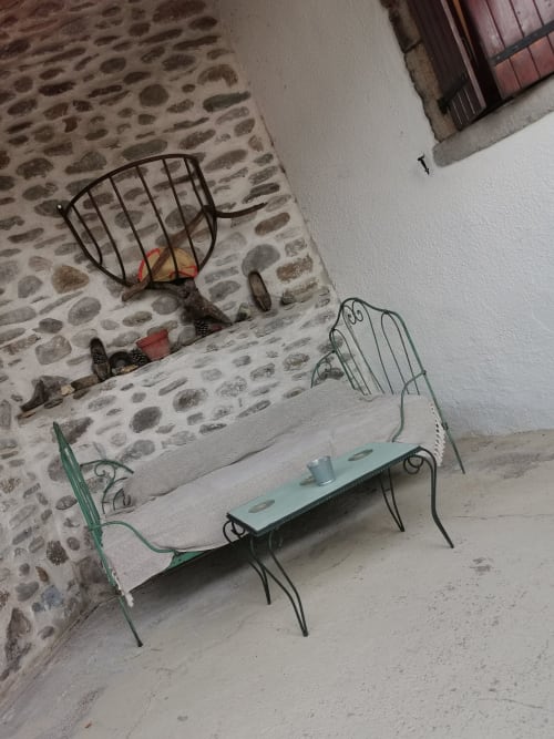 Rustic courtyard at French gîte with decorative metal chairs and basket near stone walls, Gagnières