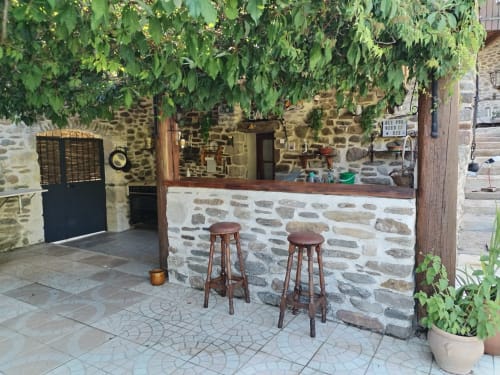 Rustic stone bar with wooden stools and ivy-covered entrance at French gîte in Gagnières