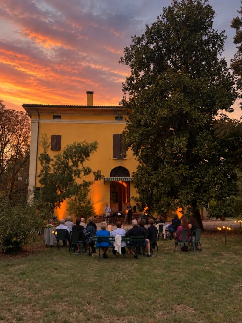 Riunione al tramonto presso Palazzo Bonfiglioli a San Giovanni in Persiceto, Italia, con ospiti seduti davanti a