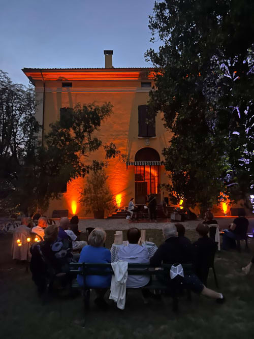 Serata nel cortile del Palazzo Bonfiglioli a San Giovanni in Persiceto con ospiti seduti di fronte all'illuminazione