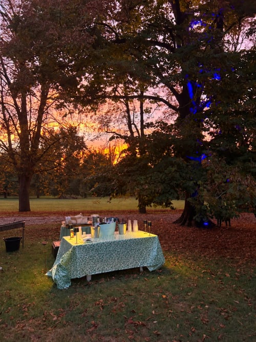 Elegante tavolo esterno al tramonto con candele e illuminazione blu sotto gli alberi a Palazzo Bonfiglioli, San Giovanni in