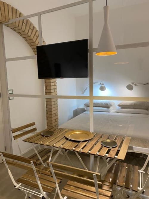 Moderno monolocale al B&B Il Giardino di Ulisse a Reggio Calabria con zona pranzo, TV, lampada a sospensione e vista camera da letto