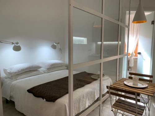 Camera moderna a B&B Il Giardino di Ulisse, Reggio Calabria, con divisorio in vetro, biancheria bianca e design minimalista