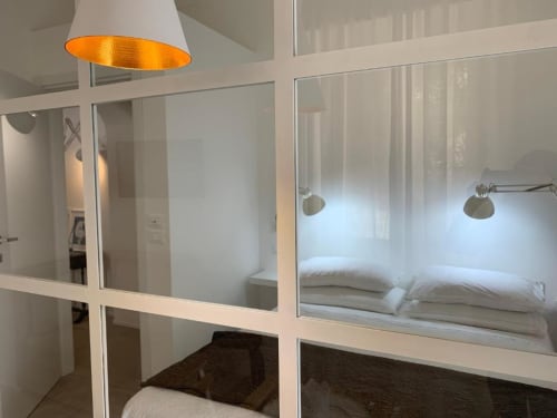 Camera moderna con divisorio in vetro, lampada a sospensione e letto impeccabile presso B&B Il Giardino di Ulisse, Reggio