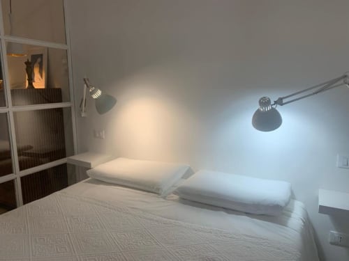 Camera moderna in B&B Il Giardino di Ulisse, Reggio Calabria con letto bianco, cuscini e lampada da parete orientabile