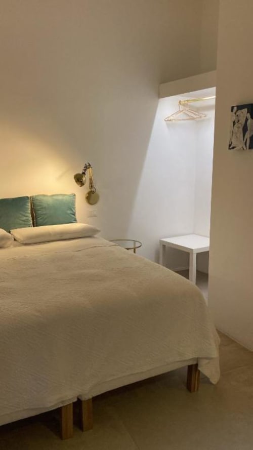 Camera moderna presso il B&B Il Giardino di Ulisse a Reggio Calabria con testata verde, dettagli in ottone, biancheria bianca