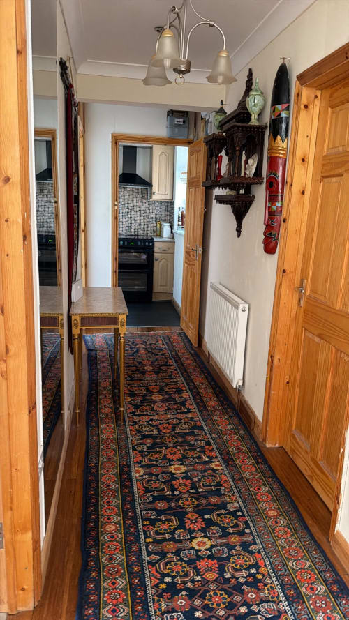 Narrow hallway with ornate patterned runner rug, wooden doors, pendant lighting, and wall decorations in High Wycombe