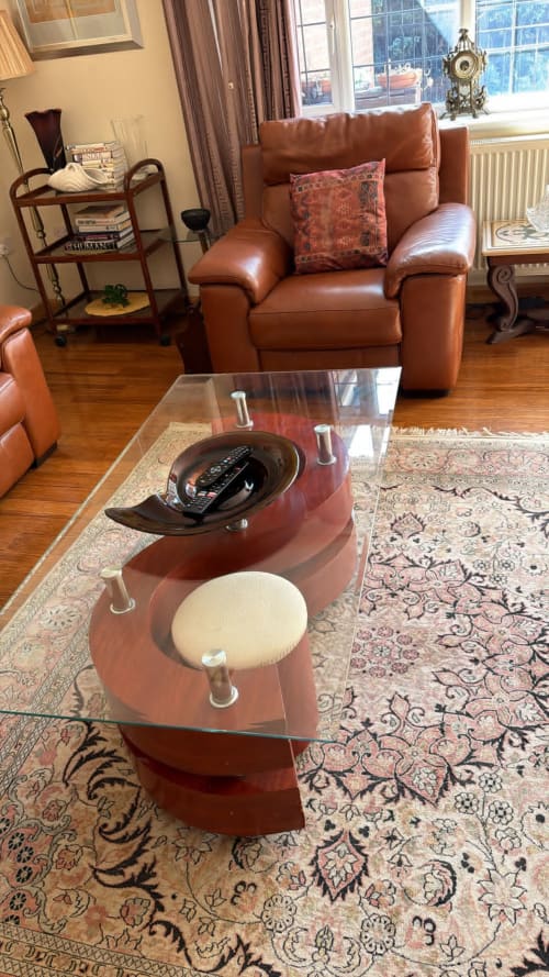 Modern living room at England Furnished Homes with brown leather armchair, glass coffee table, patterned rug, and garden view