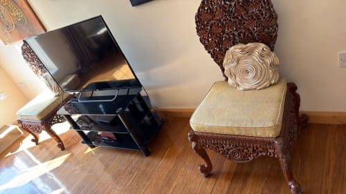 Ornately carved wooden chair with cream cushion beside black TV stand in furnished High Wycombe property