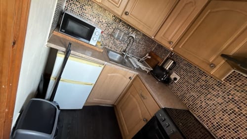 Modern kitchen with brown cabinets, microwave, sink, and black appliances in furnished 2BR High Wycombe property