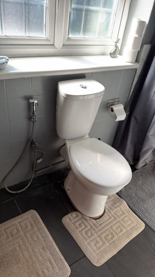 Modern white toilet and bidet in bathroom at England Furnished Homes, High Wycombe with tiled walls and window view