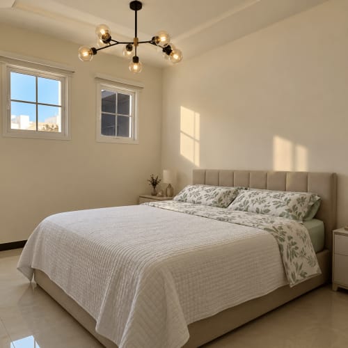 Bright modern bedroom at Palazzo di Donna with beige bed, pendant lighting, and windows overlooking Italian landscape
