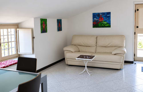 Spazioso soggiorno con 2 camere a Palazzo di Donna: divano beige, opere d'arte colorate e luminoso design italiano