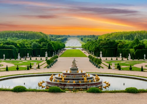 Fontaine ornée et jardins à la française du Palais de Versailles près de Sèvres, France au coucher du soleil