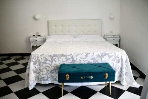 Elegant double bedroom at Palazzo di Donna hotel with white upholstered headboard, teal vintage suitcase, black and white