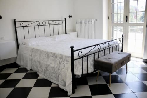 Elegantly appointed double bedroom at Palazzo di Donna with ornate iron bed, white bedding, and black-and-white tiled floor