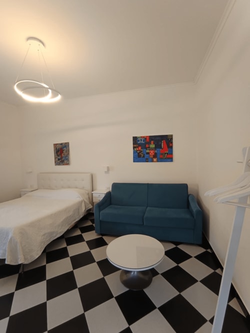 Modern hotel room at Palazzo di Donna with bed, blue sofa, round table, and black and white checkered floor