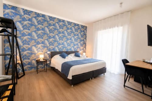 Camera matrimoniale deluxe a Le Rooms B&B in Italia con carta da parati a motivi blu, accesso al balcone e arredi moderni