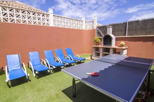 Außenterrasse der Villa Sara & Gino in Corralejo mit blauen Liegen, Tischtennisplatte und Steinkamin