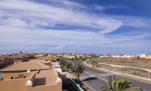 Luftaufnahme der Villa Sara & Gino in Corralejo mit Terrakotta-Dächern, Palmen und Küstenlandschaft unter blauem Himmel