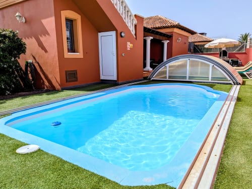 Blauer Swimmingpool mit Schutzabdeckung in Villa Rodrigo in Corralejo, Fuerteventura, mit Terrakottahaus