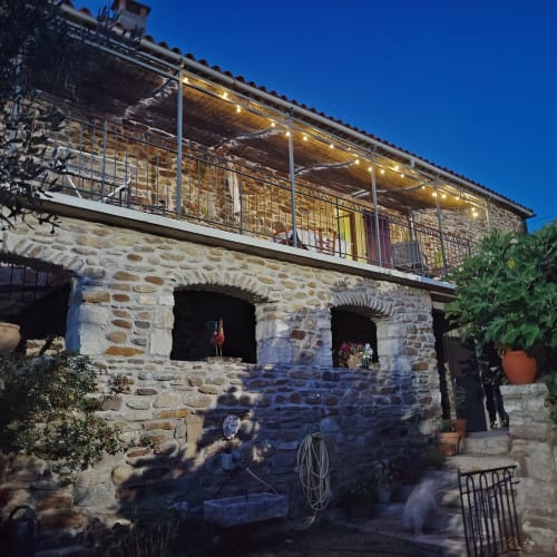 Mes Maisons stone villa in Gagnières, France with illuminated terrace and arched entrance at dusk