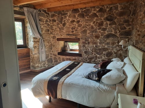 Acogedora habitación de piedra en Bikarte Alojamientos con ropa de cama blanca, vigas de madera y vistas al jardín en Ribeira Sacra