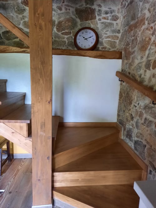 Escalera de madera con muros de piedra y reloj redondo en apartamento Bikarte Alojamientos, Ribeira Sacra