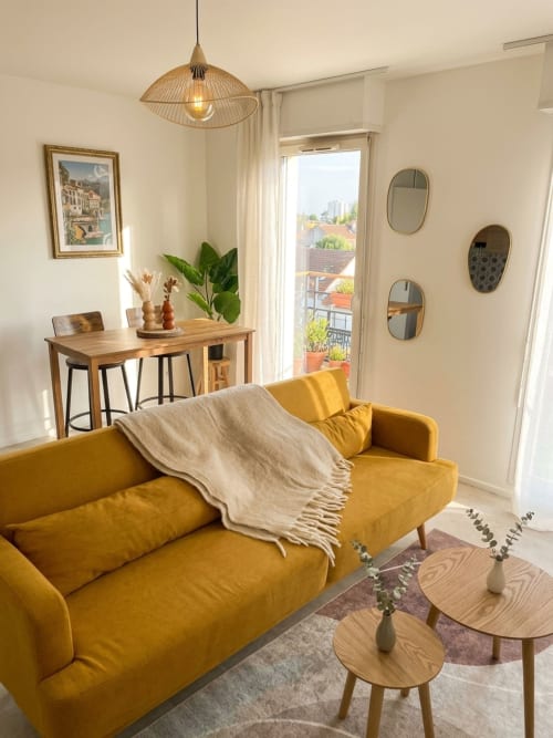 Lumineux séjour parisien avec canapé jaune, bureau en bois, lampe suspendue et vue sur balcon à Montmagny