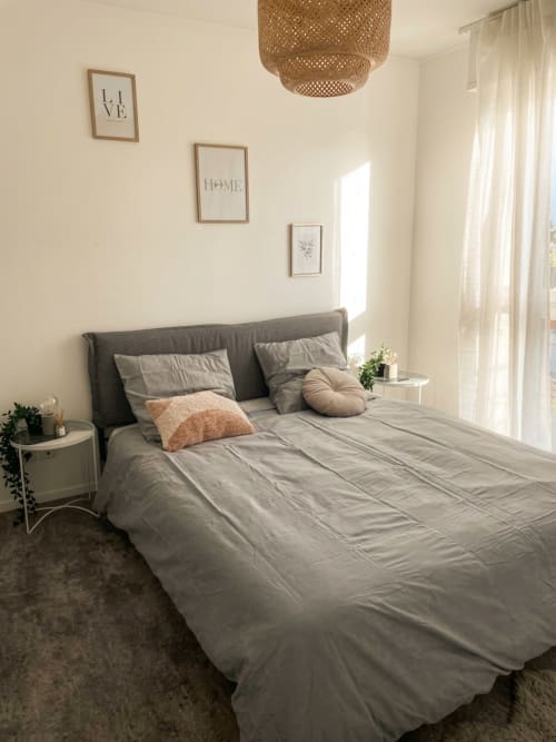 Chambre moderne à l'appartement Le Petit Paradis Parisien avec lit gris, suspension en osier et vue sur la ville