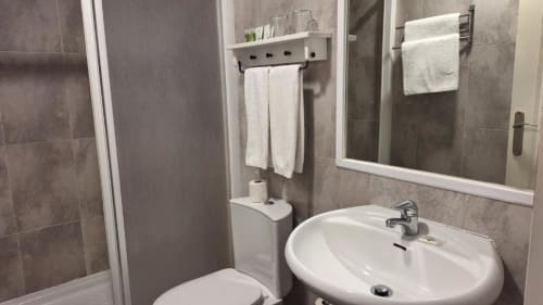 Baño moderno y limpio en Hostal San Vicente II de Sevilla con lavamanos, inodoro y paredes alicatadas