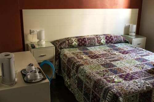 Habitación con cama matrimonial en Hostal San Vicente II, Sevilla, con edredón de patchwork, mesitas de noche y espejo