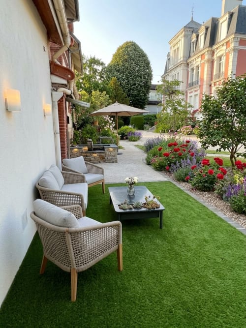 Élégante terrasse de jardin au Paradis Des Logis avec mobilier en rotin, fleurs rouges et vue sur l'architecture parisienne