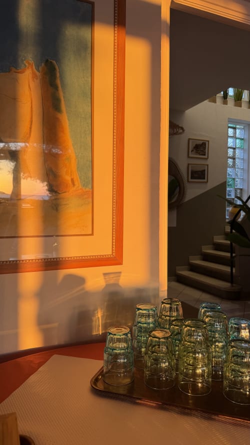 Couloir baigné de lumière dorée à l'Hôtel Thalassa avec tableaux encadrés et vases en verre sur table
