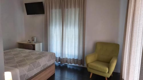 Habitación doble espaciosa en Hostal San Vicente II de Sevilla con cama, sillón verde y comodidades modernas