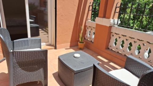 Zona de estar en terraza del Hostal San Vicente II Sevilla con muebles de mimbre y pared naranja