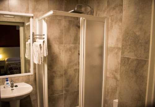 Baño moderno con ducha de azulejos en Hostal San Vicente II de Sevilla, con lavabo y espejo
