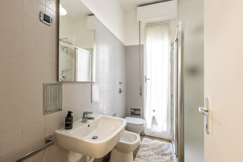 Bagno moderno nell'appartamento Solumnia Urban Nest 2 a Milano, con lavabo bianco, wc, cabina doccia e pareti piastrellate