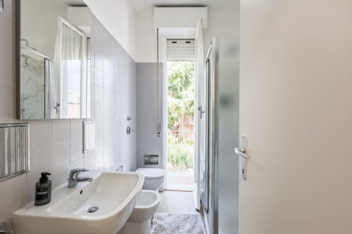 Bagno moderno nell'appartamento Solumnia Urban Nest 2 Milano con lavabo, wc, doccia, specchio e vista sulla porta del giardino