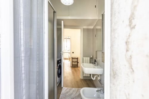 Moderno bagno dell'appartamento Solumnia Urban Nest 2 a Milano, con lavabo bianco, lavatrice e pavimento in legno