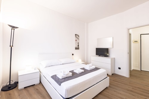 Camera moderna in Solumnia Urban Nest 2, Milano - letto bianco, TV, pavimenti in legno, design minimalista