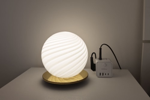 Lampada globo bianca a spirale su base in ottone con adattatore USB presso l'appartamento Solumnia Urban Nest a Milano