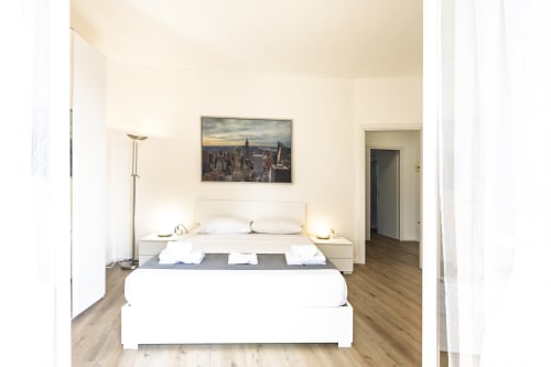 Camera moderna in Solumnia Urban Nest 2, Milano con letto queen size, biancheria bianca, pavimenti in legno e vista skyline