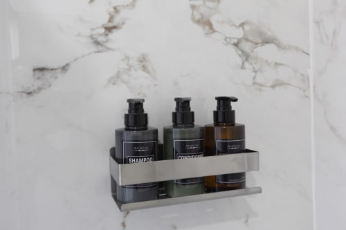 Scaffale con articoli da bagno, bottiglie di shampoo e balsamo nell'appartamento Solumnia Urban Nest a Milano