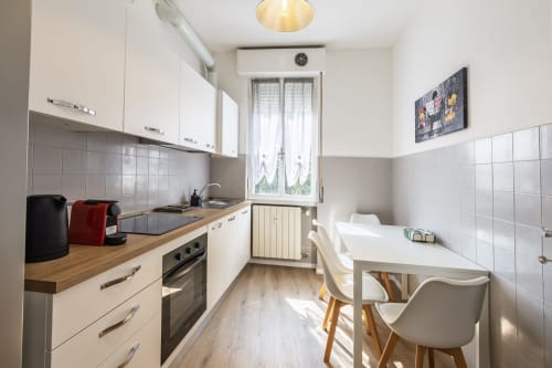 Cucina moderna con zona pranzo nell'appartamento Solumnia Urban Nest 2 a Milano. Armadi bianchi, top in legno, completamente attrezzata